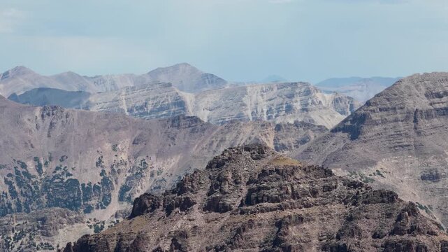 Aerial of rugged mountain plateau in Uinta Wasatch Cache National Forest Utah with vast arid canyons and heavily eroded desert terrain under a summer sky