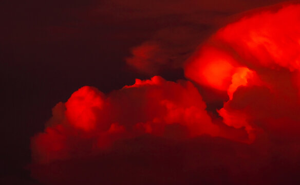 Fiery red cumulonimbus storm clouds glowing dramatically at sunset, creating an intense atmospheric background for climate, extreme weather, disaster and dramatic sky concepts.
