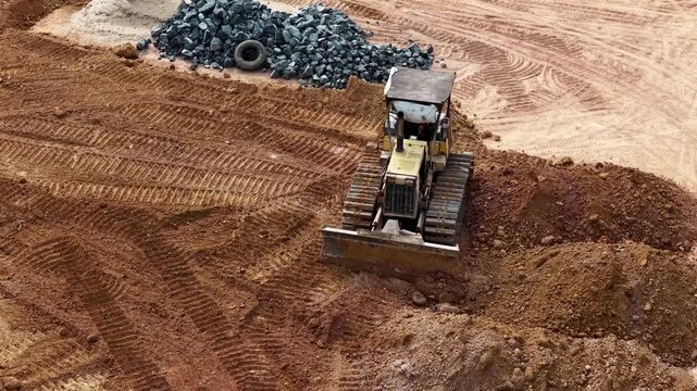 Yellow bulldozer clears dirt and levels the ground at a construction site in Banjarbaru