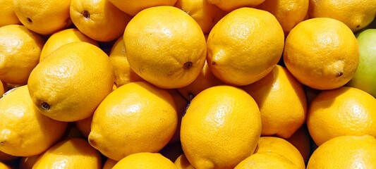 High angle view of ripe yellow lemons stacked neatly on a local farm market stand © EfendyA