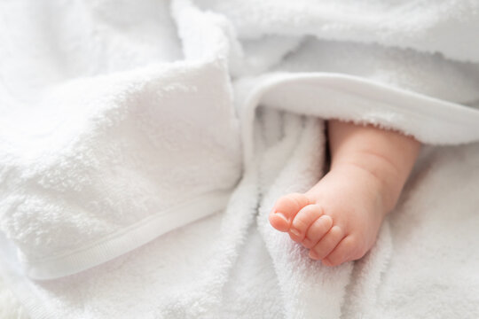Infant's imprint: baby foot shyly emerging from white fabric