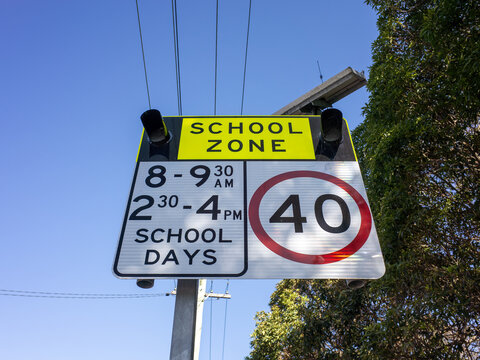 An Australian school zone road sign featuring flashing lights, operating hours, and a 40 km/h speed limit emblem against overhead powerlines in Sydney, New South Wales, Australia.