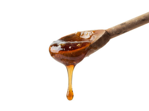 Dark amber organic honey dripping from a rustic wooden spoon on white background