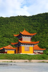 Fototapeta premium Traditional Chinese Pagoda Temple Surrounded by Green Mountains in Phnom Sruoch, Kampong Speu, Cambodia