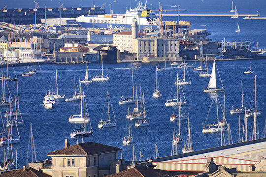 Trieste, Italy -10 October 2010: View of the Barcolana Regatta with numerous sailboats in the harbor, historic buildings, and a lighthouse in the background.
