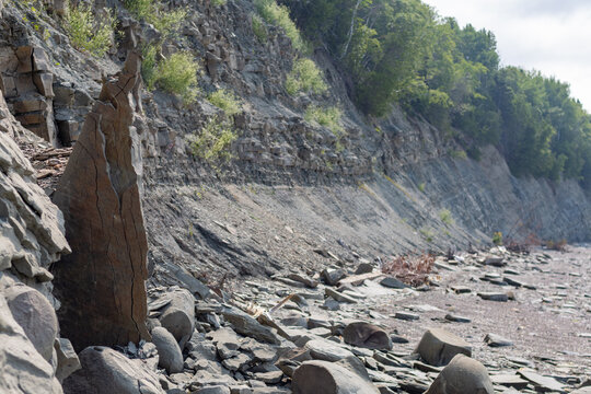 Quebec, Canada, 28 July 2026 : A tall, cracked rock formation rises from a rocky ground at the base of a steep cliff.