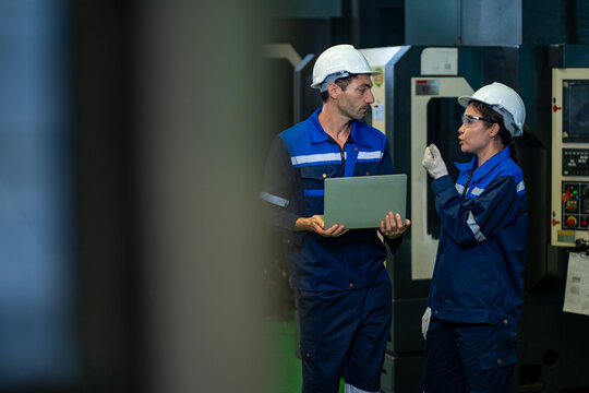 Team of industrial worker is checking the setup value of  metal casting machine by automated monitor while working inside roof factory for safety industry