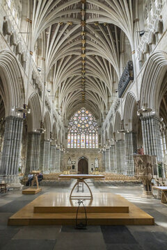Exeter, United Kingdom - 22 July 2026: View of the interior of Exeter Cathedral featuring the nave with its long vaulted ceiling, stone columns, stained glass window, and wooden altar.