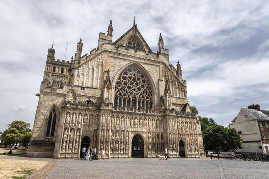 Exeter, England, United Kingdom - 22 July 2026: View of the ornate Gothic facade of Exeter Cathedral with intricate stone carvings, a large rose window, and people on the square.