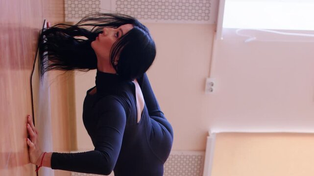 Vertical video. Gymnastics balance. Stretching exercise. Woman doing decline push up in split pose for body stability with aerial yoga hammock support.