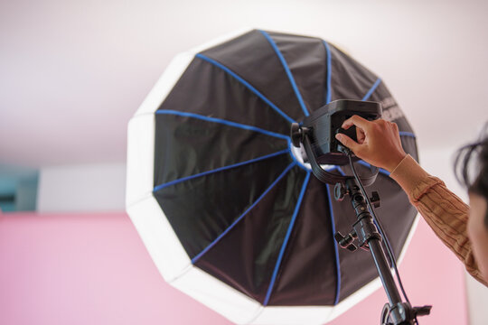 Cropped hand adjusting studio strobe light with softbox for photography production