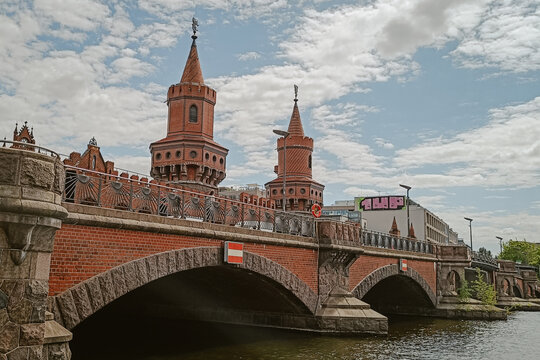 Berlin, Germany - 05 June 2026: View of the historic Oberbaum Bridge with its distinctive red brick towers and arches spanning the Spree River under a cloudy sky.