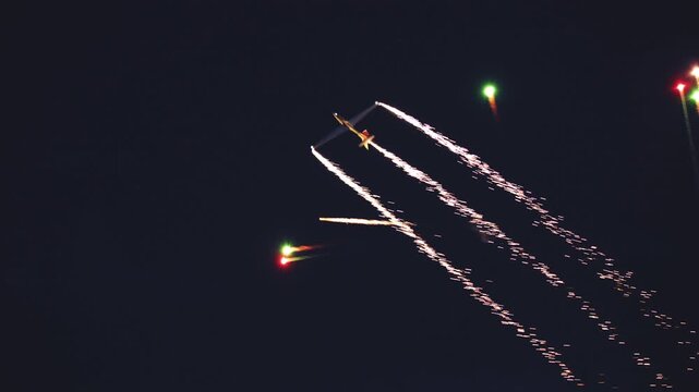 A glider performs night aerobatic maneuvers with pyrotechnic wingtip trails.