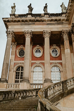 Berlin, Germany - 04 June 2026: View of the ornate facade of Charlottenburg Palace with its grand stone staircase, classical columns, and rooftop statues under a cloudy sky.