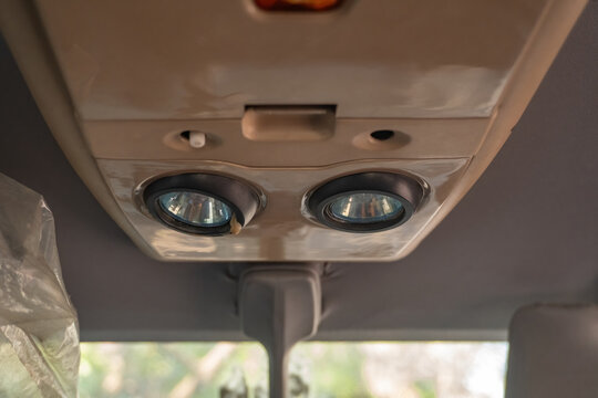 Detailed close up view of a car ceiling interior reading light cabin lamp fixture console panel during daytime.