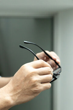 Asian elderly senior man with eyesight issue, concept image of aging eye sight, vision deterioration, elderly vision problem, hand holding eyeglasses closeup shot, home indoor scene