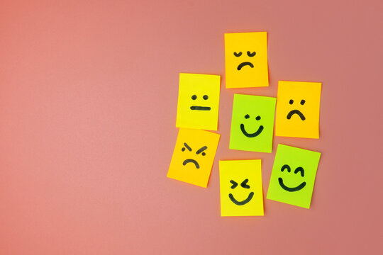 Colorful sticky notes with drawn emoticon faces expressing various emotions on a pink background. Customer feedback, mental health, evaluation, reviews concept.