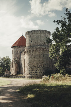 Cesis, Cesis Municipality, Latvia - 26 July 2023: View of the historic Cesis Castle with its weathered stone walls and distinctive red-roofed tower set against a bright sky.