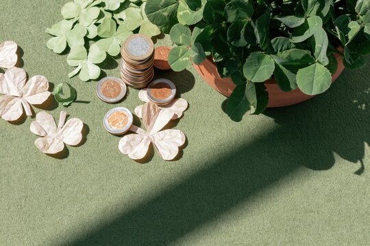 Stacked coins and paper shamrocks on a green textured surface, a whimsical St. Patricks Day flat-lay with copy space for greeting cards