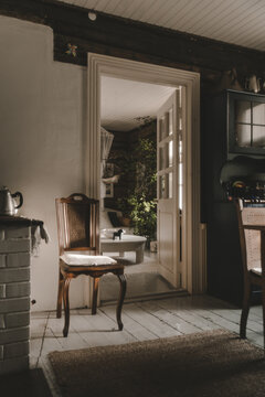 Laane County, Estonia - 25 May 2023: View of a traditional interior on Vormsi, featuring a wooden chair, a white brick fireplace, and an open doorway leading to a sunlit room.