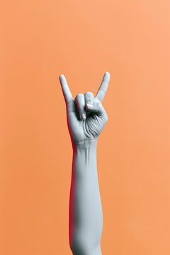 Hand making a rock gesture with glowing blue skin against a warm amber background, featuring soft lighting and copy space for music culture