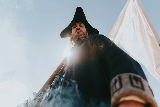 Historical reenactor in a blue 18th-century military uniform holding a musket, featuring a coarse wool texture and dramatic smoke for patriotism and heritage