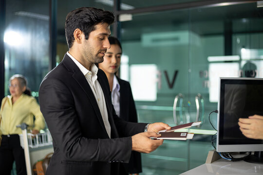 Business traveler presenting passports at office reception with woman colleague, showing travel documents, checkin, identification, corporate trip and professional service