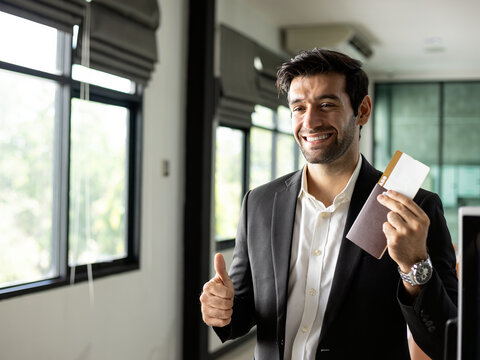 Smiling business traveler holding passport and ticket while giving thumbs up, showing travel, approval, success, confidence, positive service and professional journey