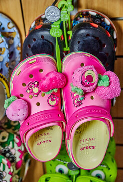 Ambato, Ecuador - November 07, 2025: Pink Crocs with Pixar character charms Jibbitz displayed on a rack among various colorful footwear in a retail store setting