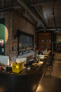 Shangrao, Guangdong, China - 07 August 2026: View of a modern industrial bar interior with exposed brick walls, a long wooden counter, bar stools, and shelves of liquor bottles.