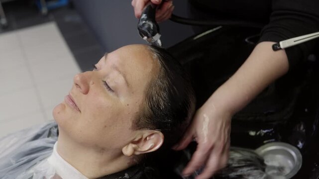 Professional barber uses electric clipper to cut male client hair indoors at salon, applying grooming technique with precision tool.