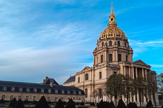 Paris, France - 04 April 2026: View of the golden dome of Les Invalides under a clear blue sky with manicured hedges in the foreground.