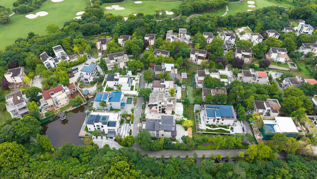 Aerial top‑down view of green‑surrounded suburban villa residential area