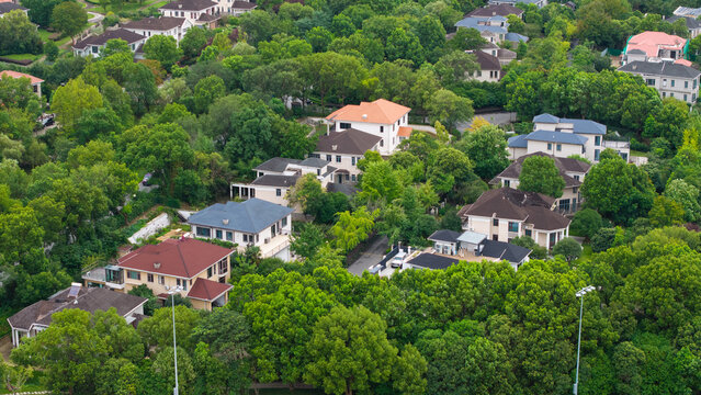 Aerial top‑down view of green‑surrounded suburban villa residential area