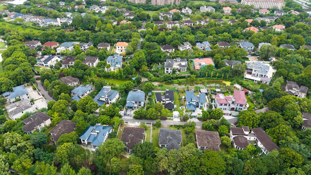 Aerial top‑down view of green‑surrounded suburban villa residential area