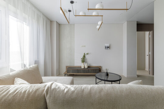 Modern Living Room Interior with Beige Sofa, TV Console, and Large Windows