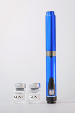 Hopeful blue medical weight loss injection pen standing next to glass vial bottle container, offering reassuring health support