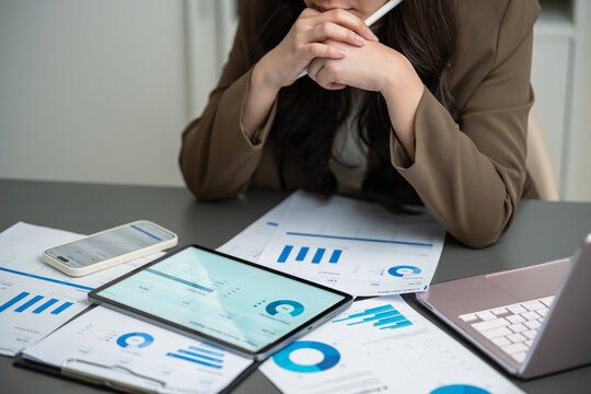 Businesswoman reviewing financial dashboards, charts and reports across tablet, laptop and smartphone, representing data analysis, business planning, performance review, strategy, and decision making.