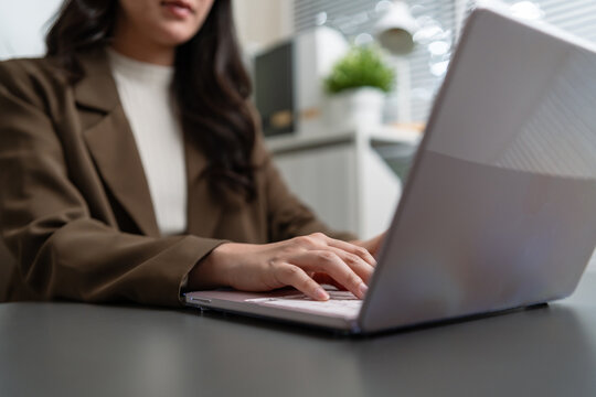 Professional businesswoman typing on a laptop at an office desk, representing online business, digital technology, corporate work, productivity, communication, management, and modern employment.