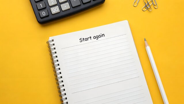 Start again concept with notebook, calculator, and pencil on yellow background