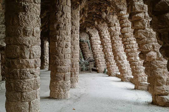 Barcelona, Spain - 04 December 2025: View of the iconic stone colonnade at Park Guell featuring rustic columns and arched walkways.