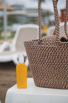 Beach scene with sunscreen and woven bag on sand