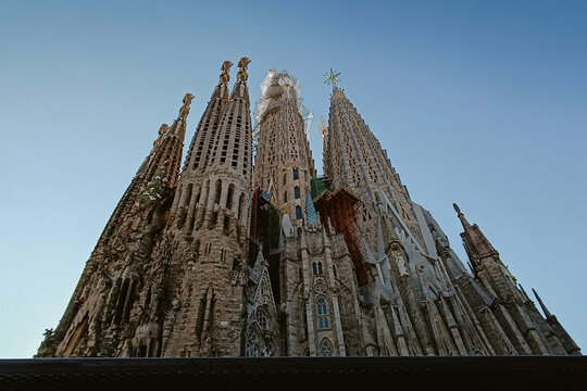 Barcelona, Spain - 03 December 2025: View of the iconic spires of the Sagrada Familia basilica rising against a clear blue sky, showcasing intricate gothic architecture and stone carvings.