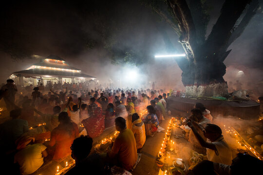 Narayanganj, Dhaka Division, Bangladesh - 09 November 2024: View of devotees gathered at a temple during a religious festival, surrounded by lit oil lamps and incense smoke at night.