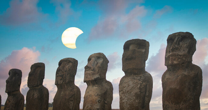 Close up Moai stone heads on Easter Island against blue sky with solar eclipse and copy space