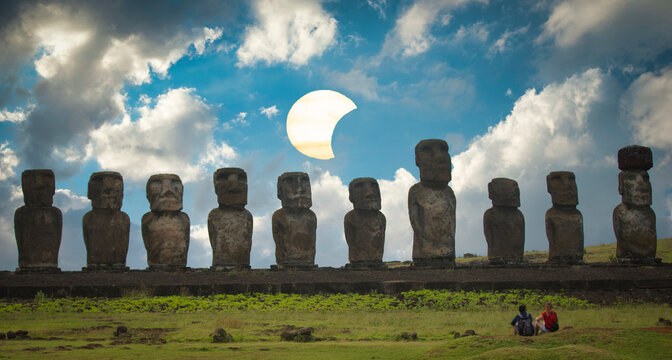 Moai statues on Easter Island at Ahu Tongariki against blue daylight sky with solar eclipse and copy space