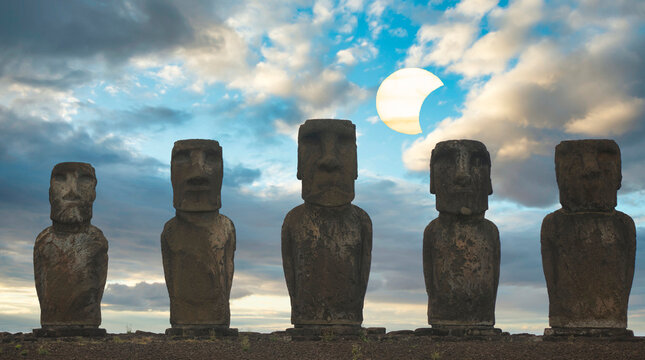 Close up Moai stone statues on Easter Island against cloudy sky with solar eclipse and copy space