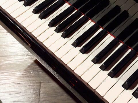 Vertical close-up of piano keys with copy space on wooden floor background for music education, concert, and art concepts. High quality