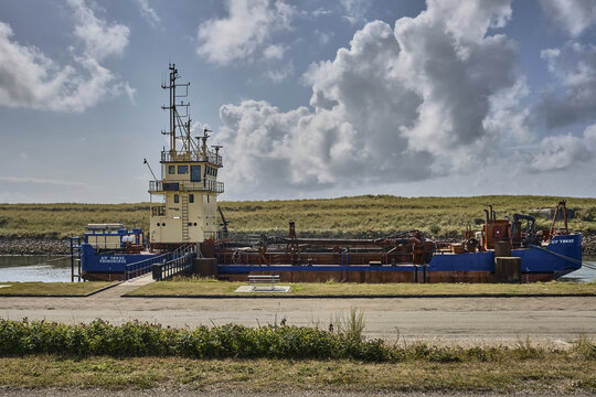 Thorsminde, Denmark - 02 August 2026: View of the trailing suction split hopper dredger vessel SP Tonne moored at Thorsminde harbor under a cloudy blue summer sky.