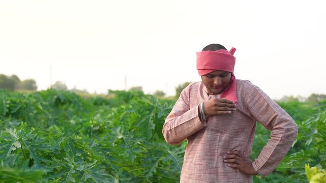 young indian farmer waling at green papaya field